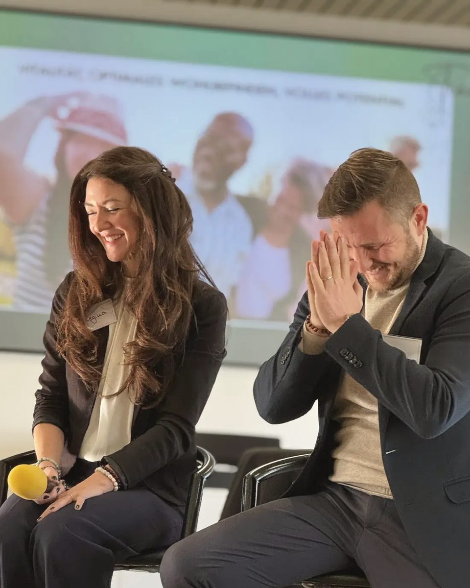 Rigina und Andreas lachen gemeinsam bei einem Seminar